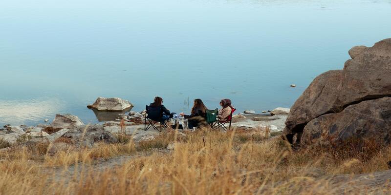 A group of people sitting on chairs by a lake AI-generated content may be incorrect.