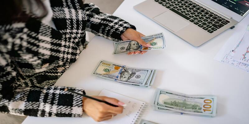 A person counting money on a table AI-generated content may be incorrect.