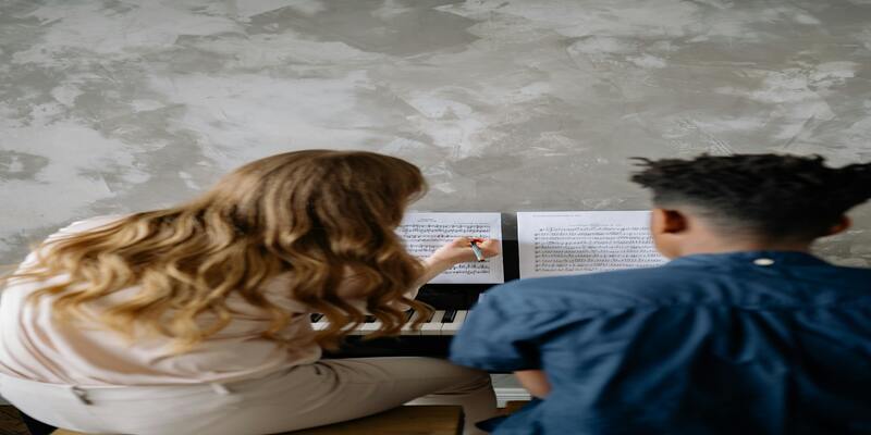 A person sitting at a piano with a person in front of her AI-generated content may be incorrect.