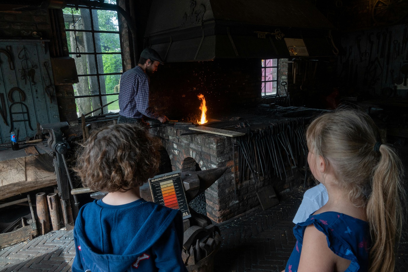 A group of kids looking at a person in a blacksmith shop AI-generated content may be incorrect.