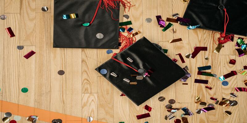 Graduation caps and confetti on the floor AI-generated content may be incorrect.