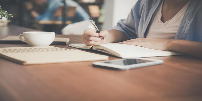 A person writing in a notebook AI-generated content may be incorrect.