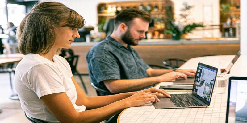 A person and person sitting at a table using laptops AI-generated content may be incorrect.