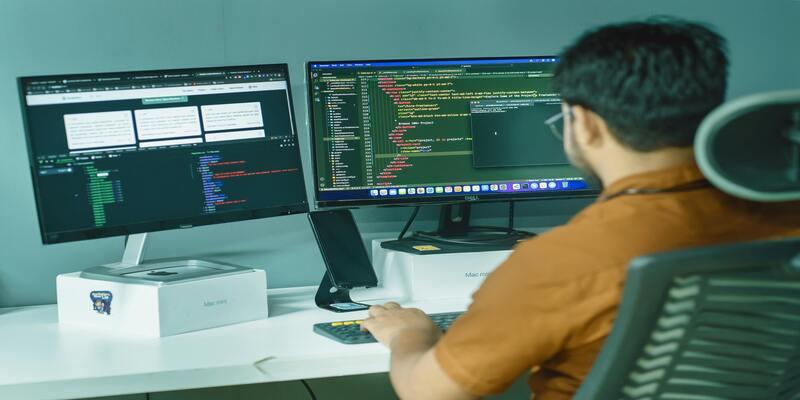 A person sitting at a desk with two computer screens AI-generated content may be incorrect.